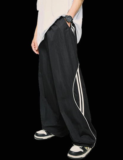 Black wide-leg pants with white stripes worn by a person on a white background